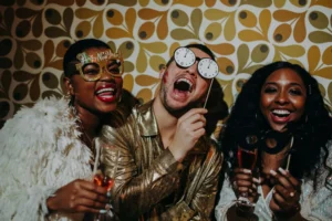 Trois invités posent avec des accessoires devant un fond graphique lors d'une soirée