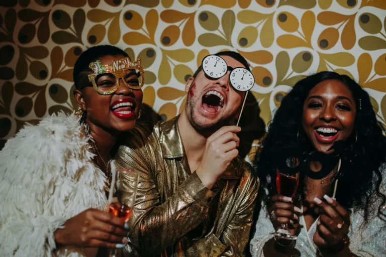 Trois invités posent avec des accessoires devant un fond graphique lors d'une soirée