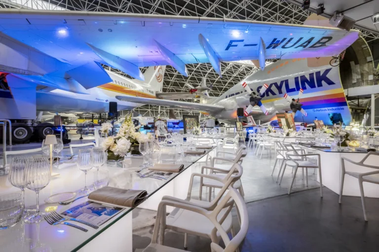 Dîner de gala dressé sous un avion, dans un hall aéronautique
