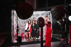 Groupe posant devant un photobooth à rideau argenté, ballons noirs en décor