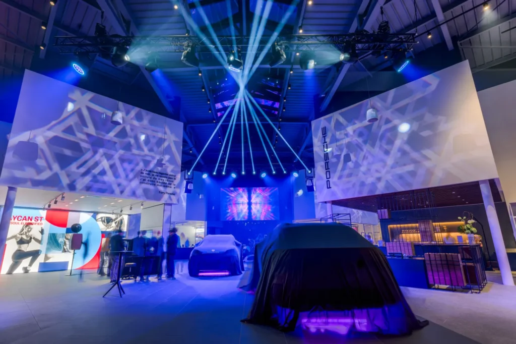 Showroom automobile éclairé en bleu, véhicule sous housse noire avant révélation