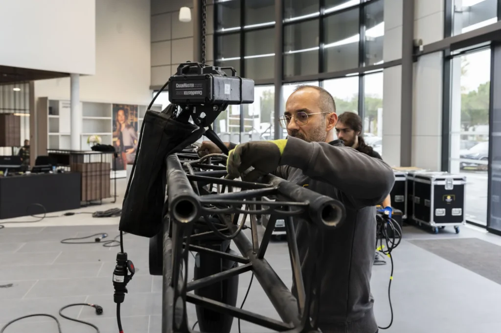 Technicien réglant un projecteur sur une structure pendant le montage d’un événement professionnel