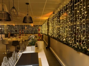 Salle habillée de rideaux lumineux dorés, suspensions noires au plafond