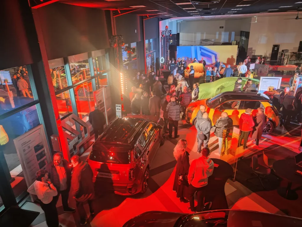 Véhicules exposés dans un showroom en éclairage rouge, visiteurs nombreux