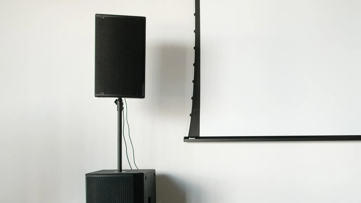 Système de sonorisation complet installé en salle, enceinte sur pied et caisson de basse