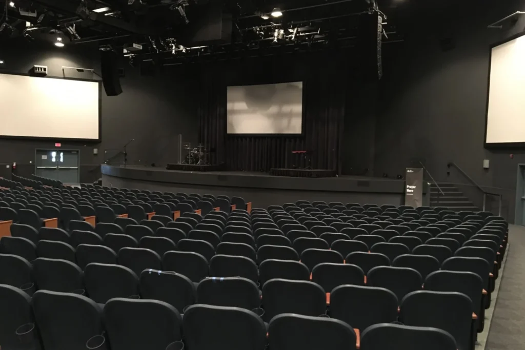Auditorium équipé d'un écran de projection, sièges orientés vers la scène