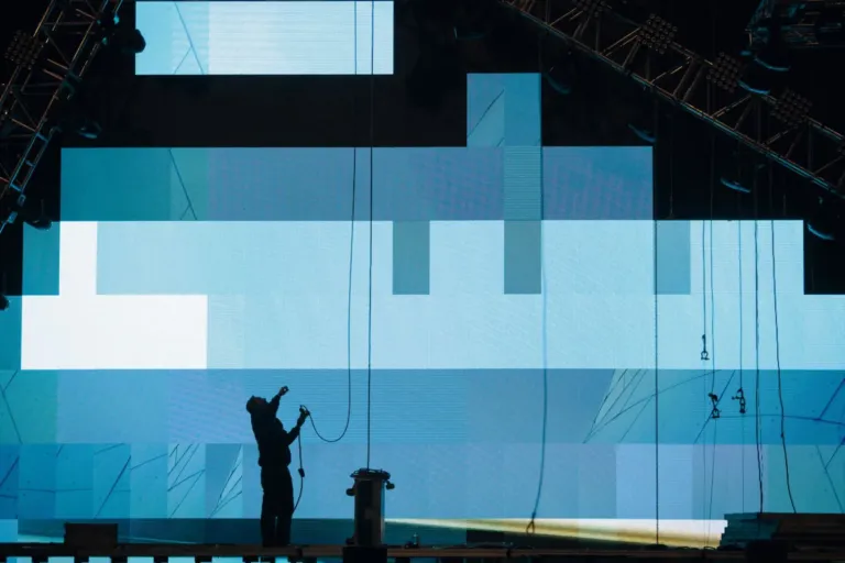Technicien devant un mur de LED en cours de montage, la grille des dalles est visible