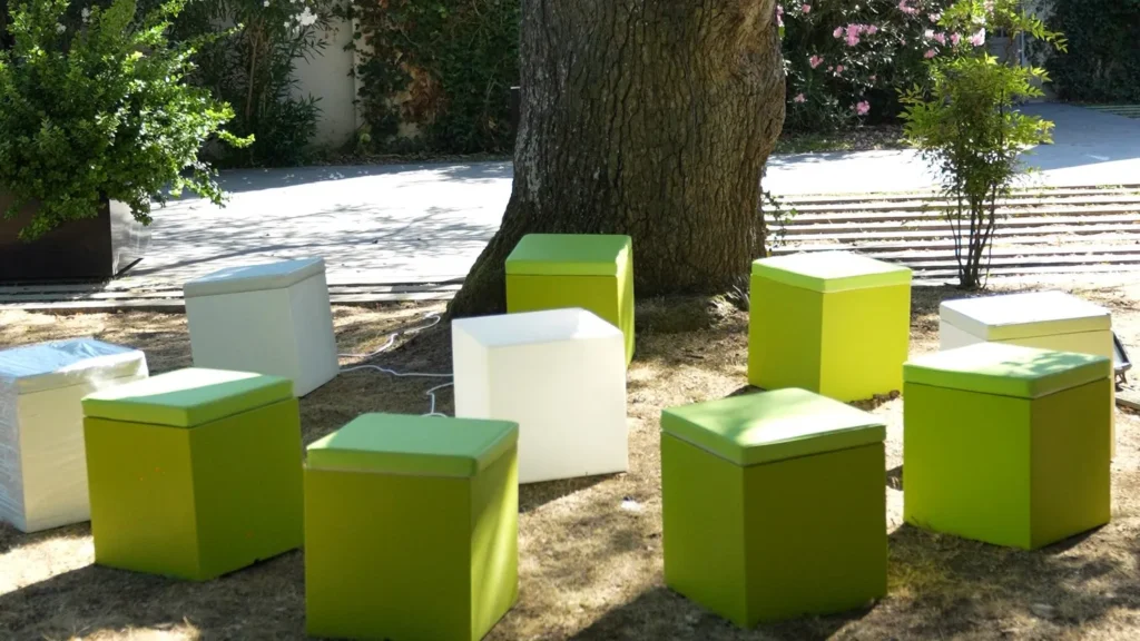 Poufs cubes vert anis et blancs installés à l’ombre d’un cèdre, réception d’entreprise en plein air au Manoir du Prince