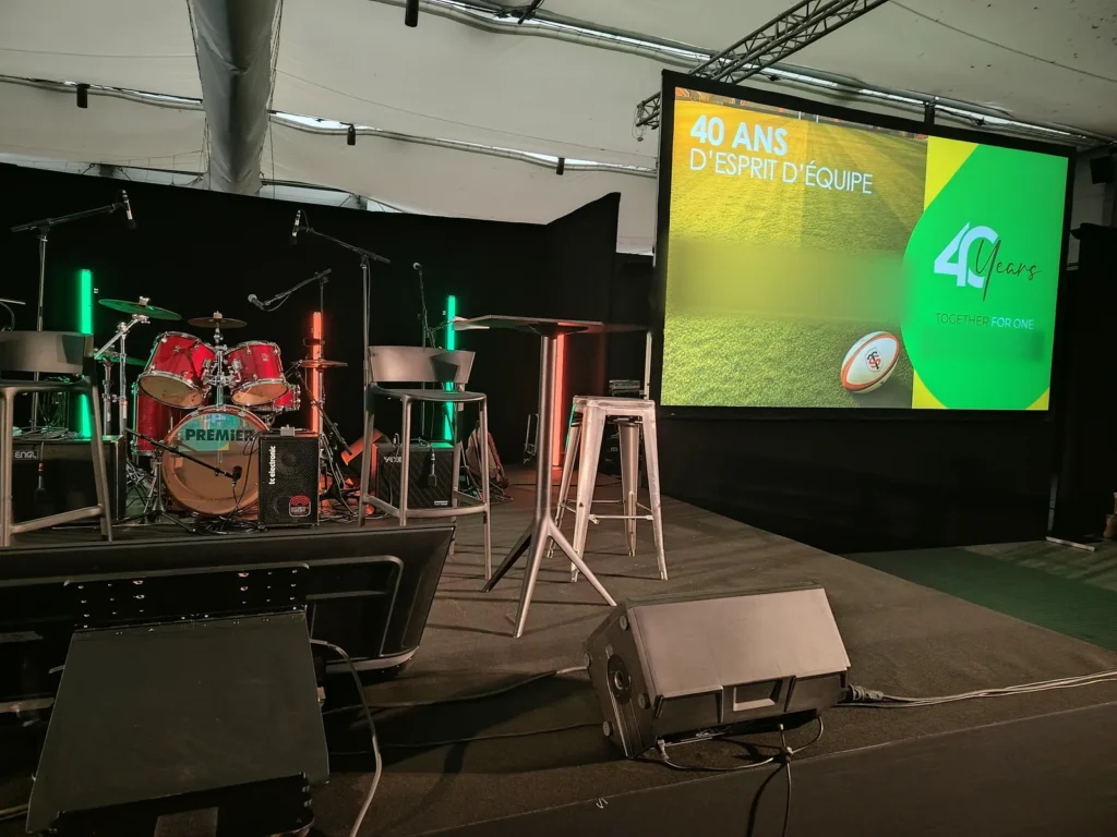 Scène de convention avec mange-debout, tabourets, batterie et tubes LED