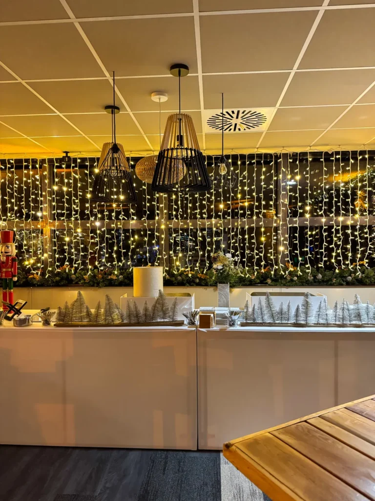 Comptoir de bar devant un rideau lumineux, petits sapins givrés et bougies posés sur le plan